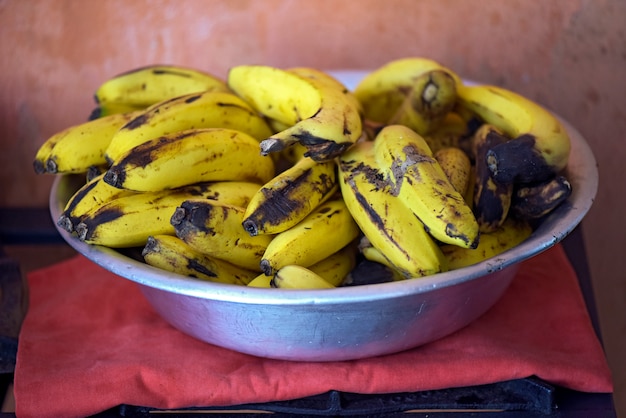 Cuenco de aluminio con racimo de plátanos muy maduros.