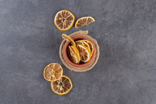 Cuenco de arcilla de limones secos en rodajas sobre fondo de piedra.