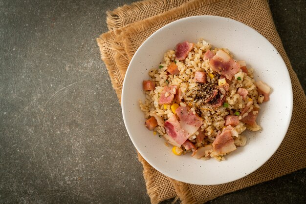 cuenco de arroz frito con tocino, jamón y pimientos negros