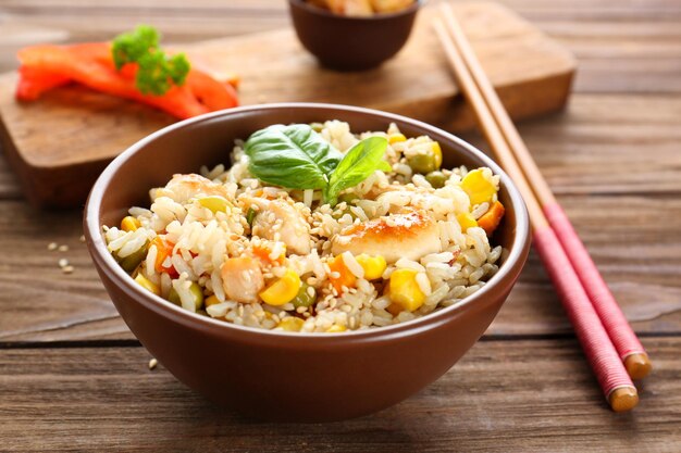 Cuenco con arroz marrón y verduras en una mesa de madera