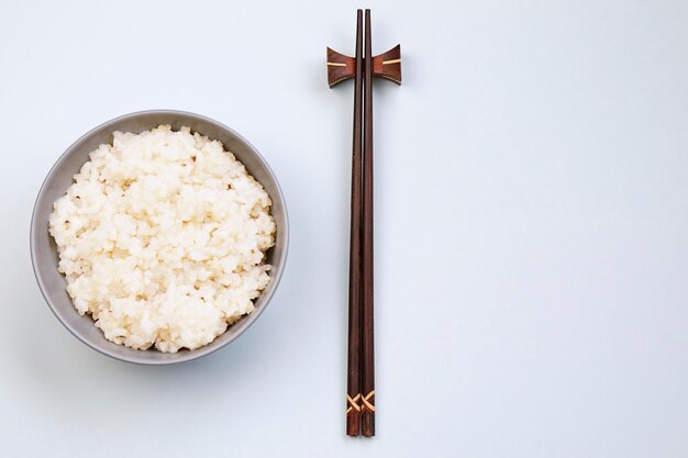 Cuenco de arroz con palillos sobre fondo neutroxA