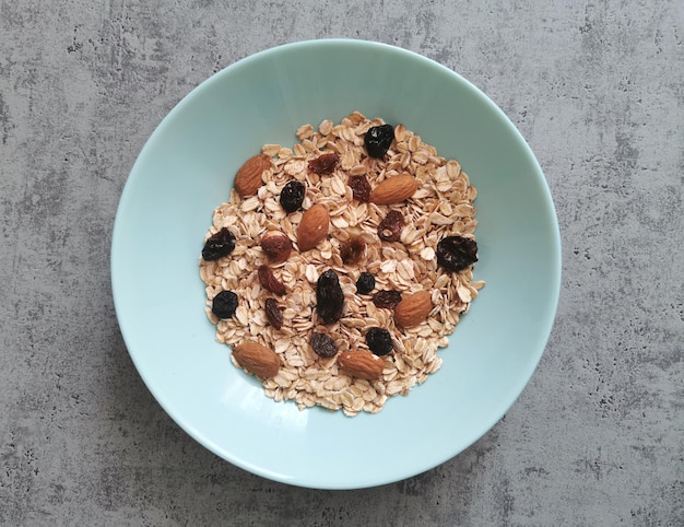 Cuenco de avena entera cruda con pasas y nueces de almendras