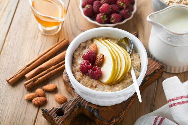 Cuenco de avena con pera de frambuesa y miel sobre fondo de mesa de madera antigua Comida caliente y saludable para el desayuno vista superior plana