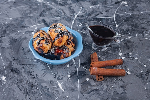 Un cuenco azul lleno de mini croissants con cobertura de chocolate en la superficie de mármol.