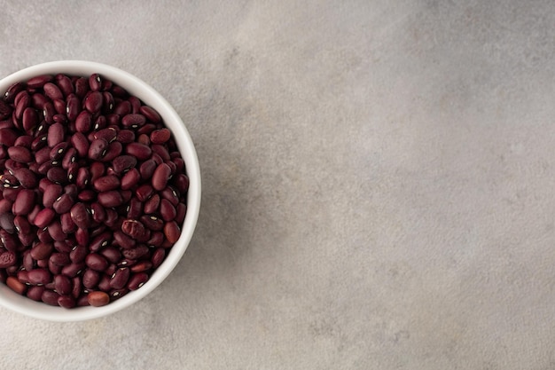 Cuenco blanco con frijoles secos rojos sobre un fondo claro