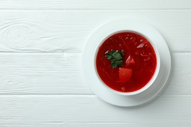 Cuenco de borscht sobre superficie de madera blanca