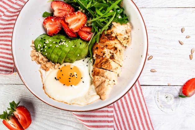 Cuenco de Buda con pollo, rúcula y fresas. Fondo de receta de comida de dieta cetogénica. De cerca