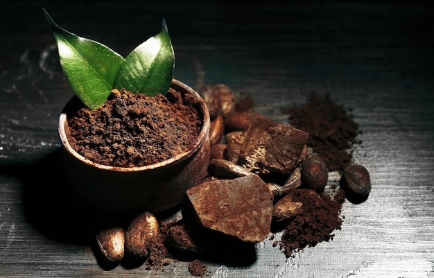 Cuenco con cacao en polvo aromático y hoja verde sobre fondo de madera de cerca