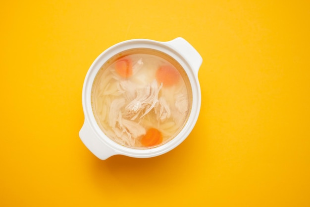 Foto cuenco de caldo de pollo con pollo y zanahoria en la oscuridad