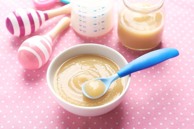 Foto cuenco de cerámica con comida para bebés sobre fondo de color