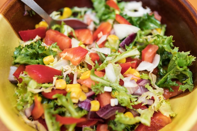 Cuenco de cerámica lleno de ensalada de primavera con tomates, maíz y verduras