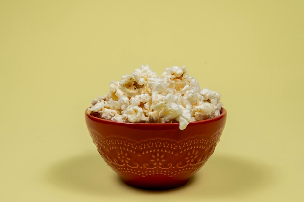 Foto un cuenco de cerámica de palomitas de maíz saladas en la mesa amarilla