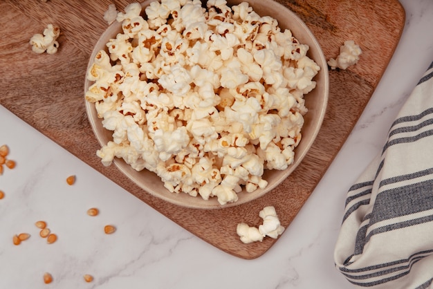 Cuenco de cerámica sobre una tabla de madera rústica con palomitas de maíz