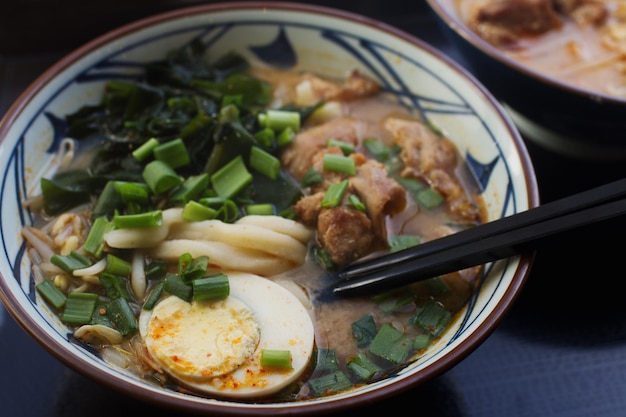 Cuenco de cerámica de sopa de ramen asiática tradicional con fideos, huevo en rodajas de pollo y champiñones