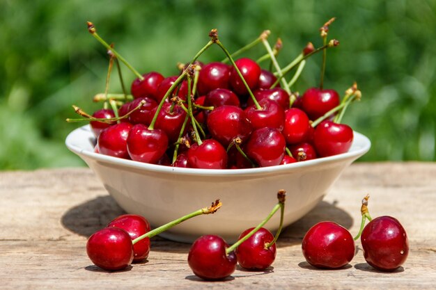 Cuenco con cereza fresca en la mesa de madera rústica al aire libre