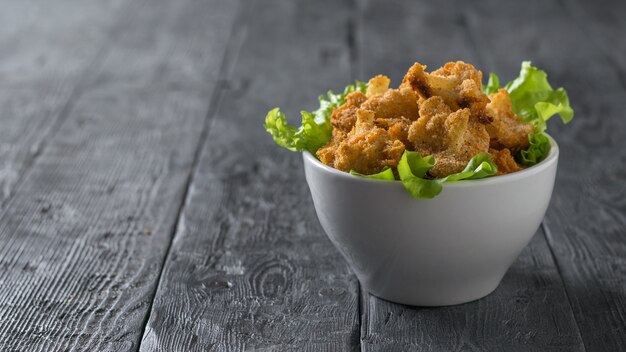 Un cuenco de color blanco profundo con coliflor al horno y lechuga sobre una mesa de madera. Aperitivo vegetariano de coliflor.