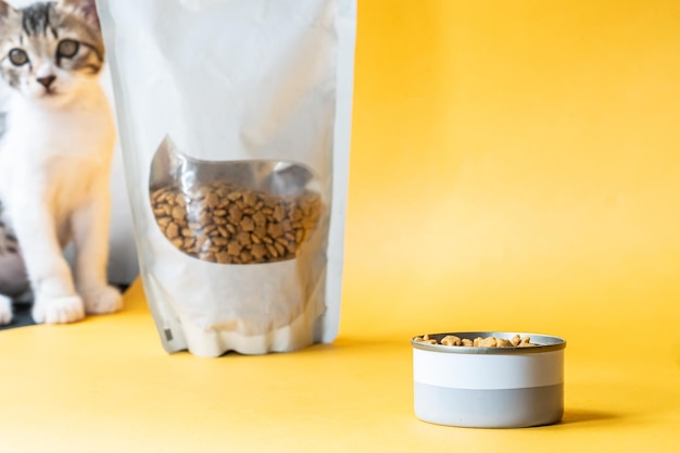 Cuenco de comida para gatos con embalaje en fondo amarillo