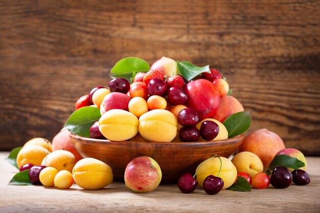 Foto un cuenco de frutas frescas maduras en una mesa de madera.