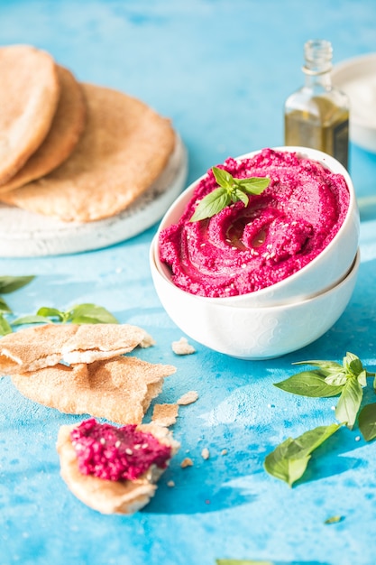 Cuenco de humus. Hummus de remolacha roja con verduras frescas, aceite de oliva en la mesa