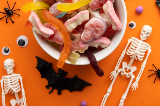 Un cuenco lleno de dulces de Halloween en un fondo naranja truco o trato de fondo