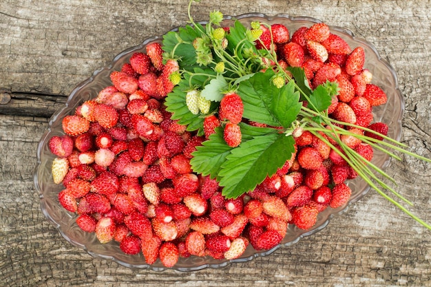 Cuenco lleno de fresas dulces y ramo fragante con bayas