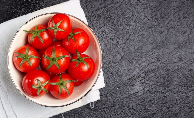 Un cuenco lleno de tomates sobre una mesa negra