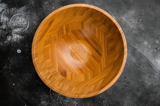 Cuenco de madera con espacio para copiar texto o comida, vista superior plana, sobre fondo de mesa de piedra oscura negra