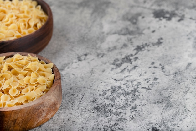 Cuenco de madera de pasta cruda colocado sobre fondo de piedra.