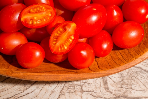 cuenco de madera con tomate de uva en el fondo de madera