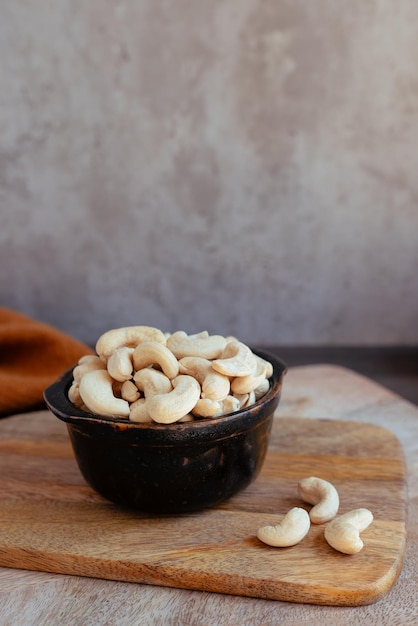 Cuenco negro con anacardos y frutos secos sobre tabla de madera