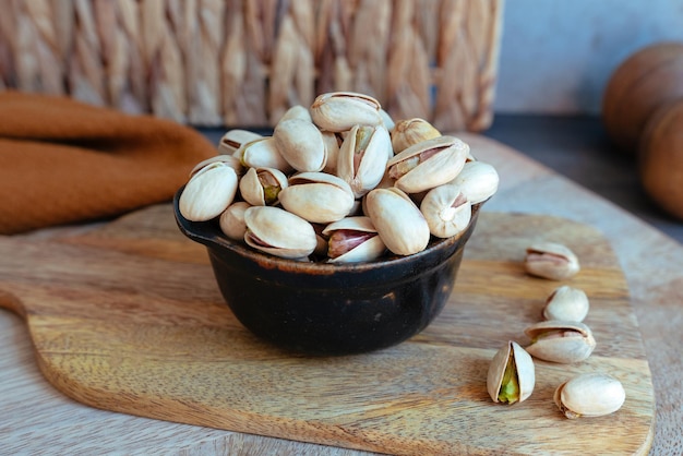 Cuenco negro con pistachos sobre tabla de madera