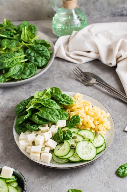 Cuenco con pasta, pepino, queso y espinacas sobre la mesa Nutrición vitamínica saludable Vista vertical Primer plano