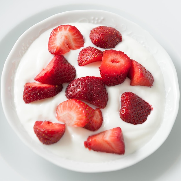 Cuenco de porcelana con fresas y nata de yogur