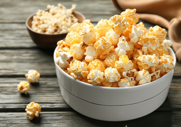 Un cuenco con sabrosas palomitas de maíz de caramelo en una mesa de madera