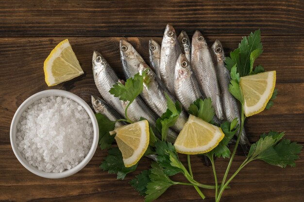 Un cuenco con sal marina gruesa y espadín con hierbas y limón sobre una mesa de madera