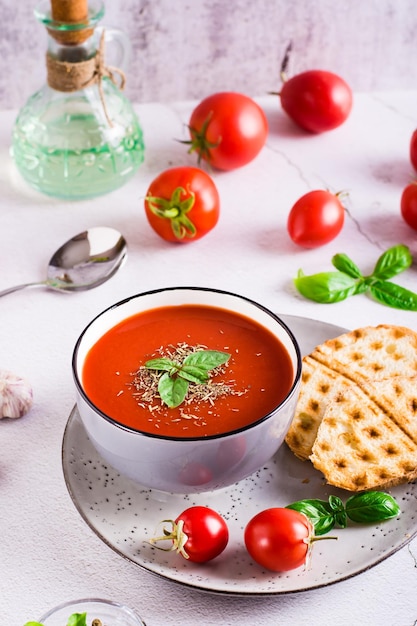 Cuenco con sopa de tomate casera con albahaca y verduras frescas en la mesa Vista vertical