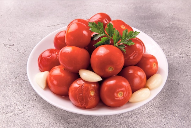 Un cuenco con tomates encurtidos y especias en un fondo gris