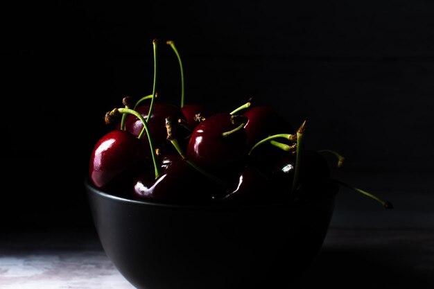 Cuenco con varias cerezas iluminadas en el estilo de comida oscura