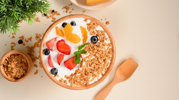 Cuenco de yogur saludable con granola integral con bayas frescas y fruta servida en la vista superior de la mesa