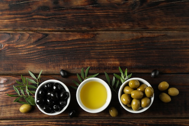 Cuencos con aceitunas y aceite en madera, espacio para texto