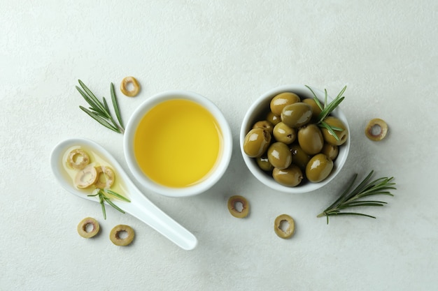 Cuencos con aceitunas y aceite sobre fondo blanco con textura