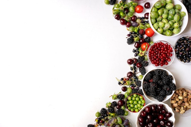 Foto cuencos con bayas frescas de cereza, frambuesa, fresa, mora, grosella, mora y espacio de copia de uva