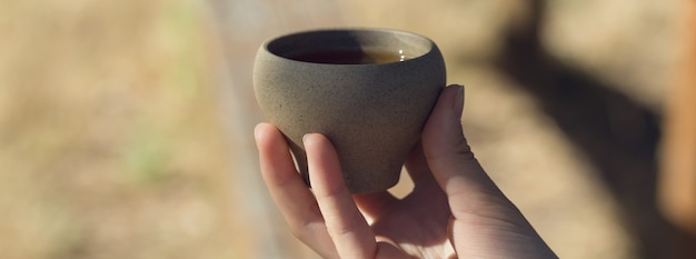 Cuencos de cerámica hechos de arcilla sobre un fondo de madera. La niña está bebiendo té chino.