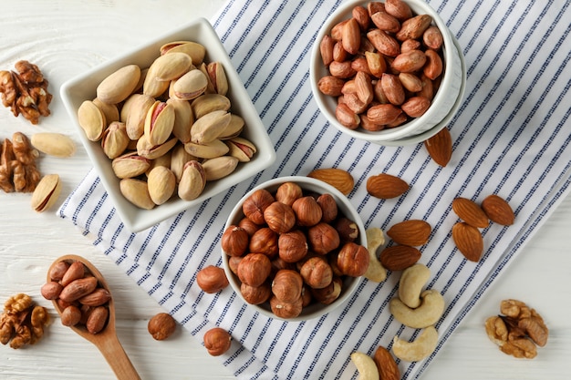 Cuencos con diferentes frutos secos sobre fondo blanco de madera. Alimentos vitamínicos