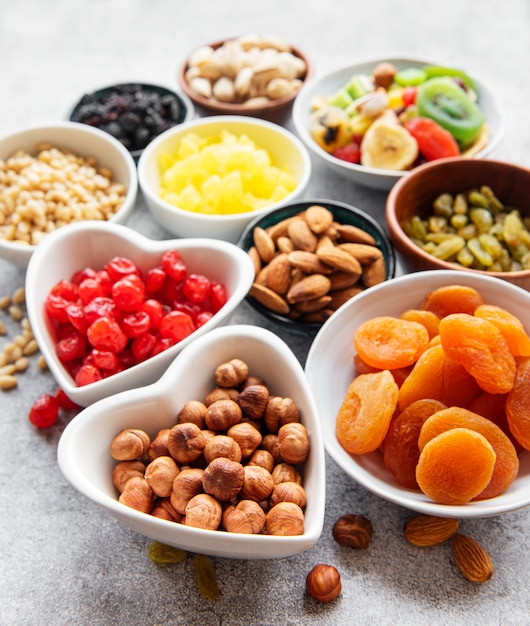 Cuencos con diversos frutos secos y nueces sobre una superficie de hormigón gris