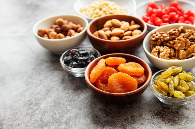 Cuencos con diversos frutos secos y nueces sobre una superficie de hormigón gris