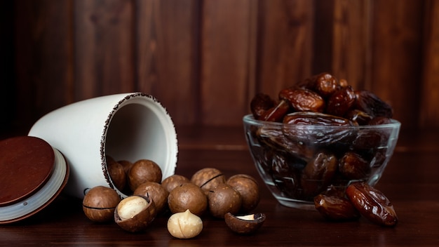 Cuencos con nueces de macadamia y dátiles en mesa de madera. Concepto de frutos secos y nueces