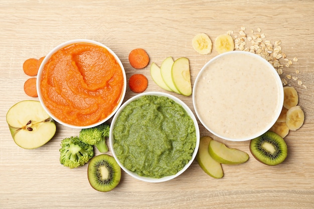 Cuencos con puré de verduras sobre fondo de madera. Comida para bebé