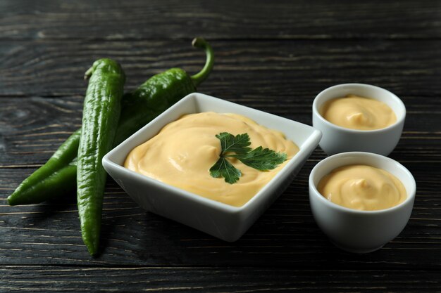 Cuencos con salsa de queso y pimienta sobre mesa de madera