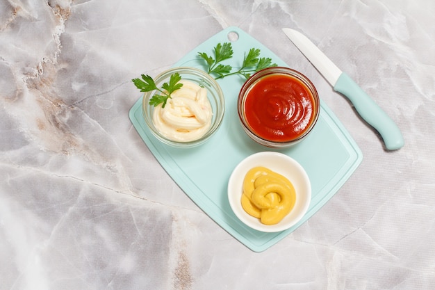 Cuencos con salsa de tomate, mostaza y queso en la mesa de la cocina.